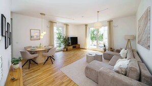 A modern living room with a sofa, a dining table, and a TV.