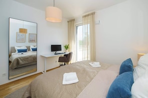 A hotel room with a bed, a desk with a computer, a chair, a large mirror, and a window with curtains. - Luxury 2-Room Apt in Scandi-Coastal-Style I Prime Location I Family-Friendly I Balcony I Kitchen I Netflix I Free Parking I 65 m2 (Eltville am Rhein)