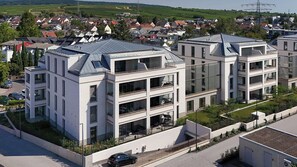 A modern multi-story residential building with balconies and a flat roof.