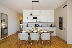 Una cocina moderna con una mesa de comedor lista para cuatro, equipada con microondas, cafetera y copas de vino.