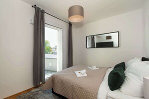 Ein Hotelzimmer mit Bett, gro ßem Fenster mit Vorhängen, Spiegel und Deckenleuchte.