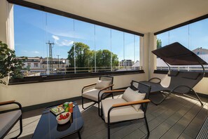 Ein Balkon mit Blick auf Gebäude, ein Tisch mit Obstschale und zwei Stühle.
