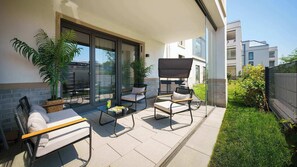 A modern outdoor patio with a dining set, two chairs, a table, and a barbecue grill.