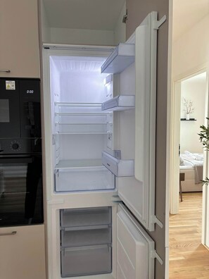 Una cocina moderna con refrigerador, horno y microondas integrados.