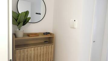 Ein Badezimmer mit einem Holzbadezimmer, einem runden Spiegel, einer Topfpflanze und einem 'HelloStay'-Schild.