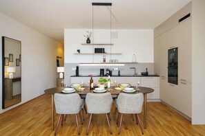 A modern kitchen with a dining table set for four, equipped with a microwave, coffee maker, and wine glasses. - Luxury 4-Room Apt in Boutique-Style I Prime Location I Family-Friendly I Balcony I Kitchen I Netflix I Free Parking I 105 m2 (Eltville am Rhein)