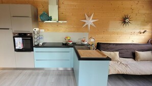 A compact kitchen with a microwave, oven, and sink, a light blue countertop, and a wooden wall with a star decoration.