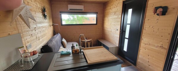 Eine kleine Küche mit Spüle, einem Fenster und einem Hocker.