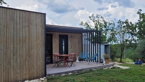 A modern wooden structure with a deck, outdoor seating, and a small garden area.