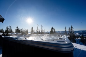 Un jacuzzi con vista despejada a un paisaje nevado y árboles al fondo.