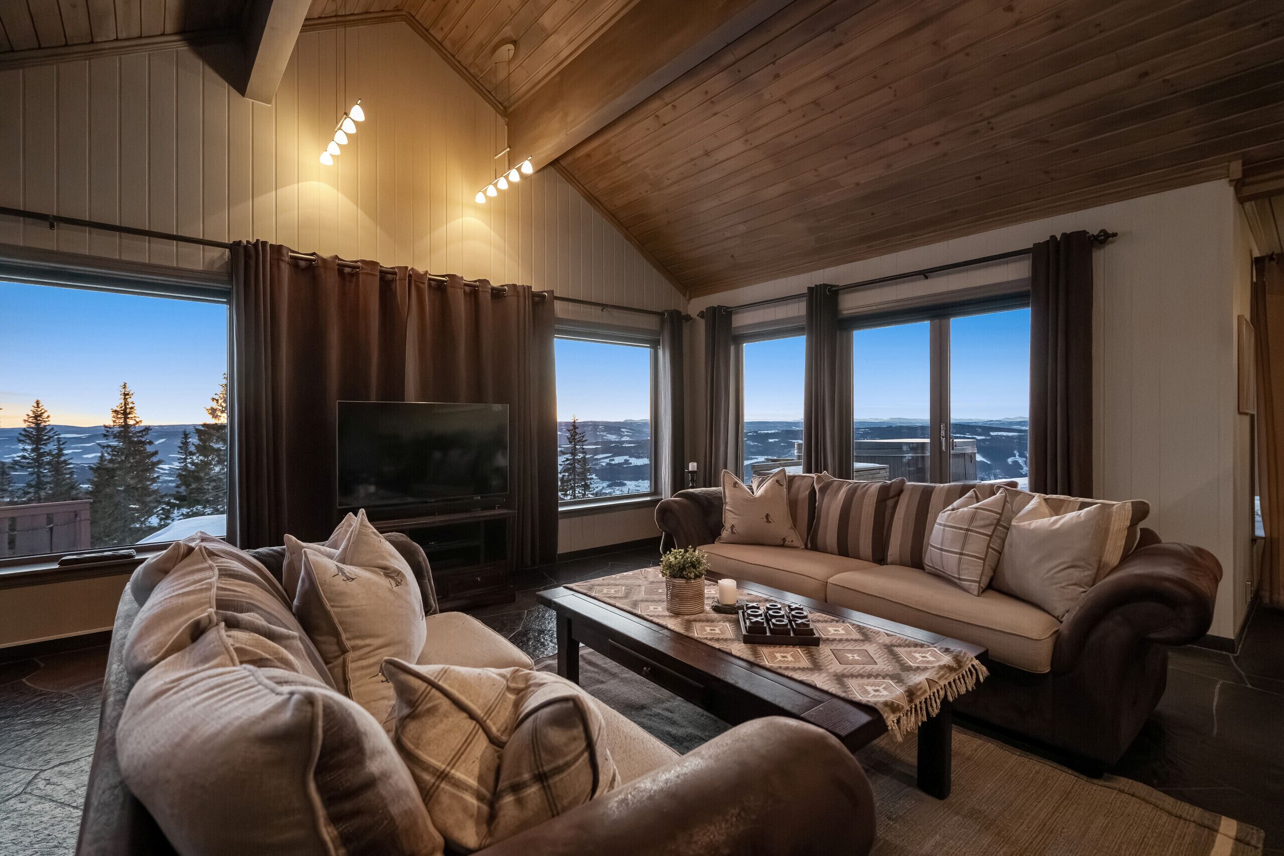 A cozy living room with a large TV, a sofa, and a coffee table.