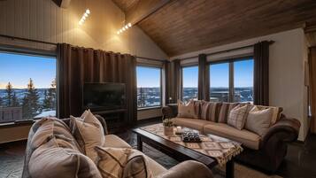 A cozy living room with a large TV, a sofa, and a coffee table.