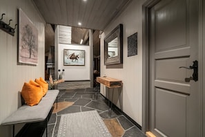 A hallway with a bench, a mirror, and artwork on the walls.