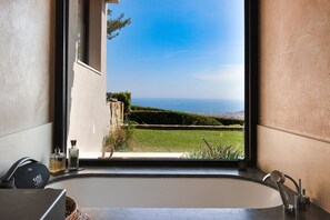 Ein Badezimmer mit großem Fenster, einer Badewanne und Meerblick.