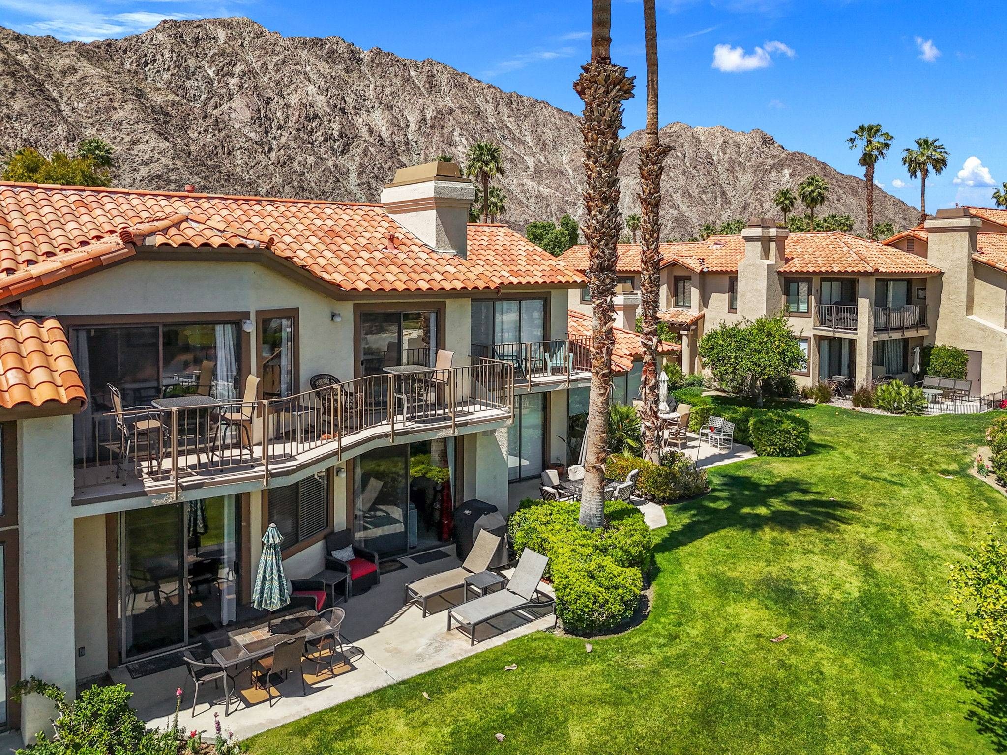 Una propiedad residencial con un amplio patio, varios balcones y un césped bien cuidado.