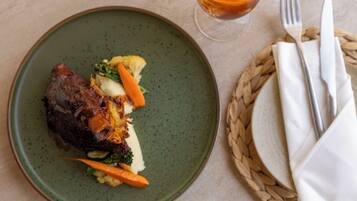 Un piatto con carne, verdure e un bicchiere di bevanda ambrata.