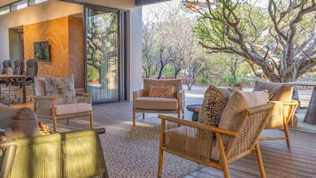 A modern outdoor seating area with wicker furniture and a view of a tree-lined landscape.