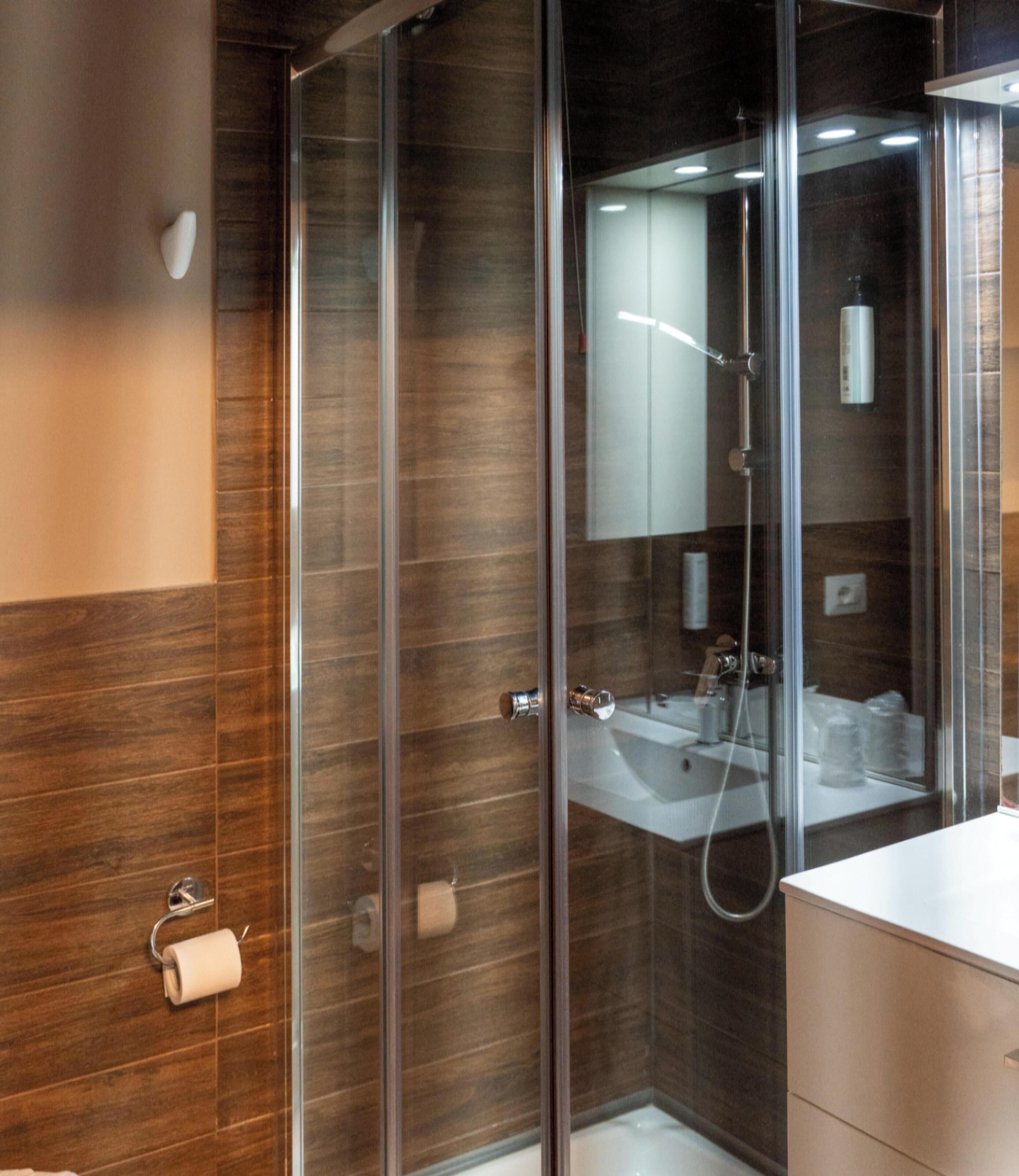 Un baño moderno con cabina de ducha de vidrio, un lavabo blanco y un espejo.