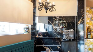 L’intérieur d’un restaurant, avec un bar en marbre, un espace salon et un appareil à café.