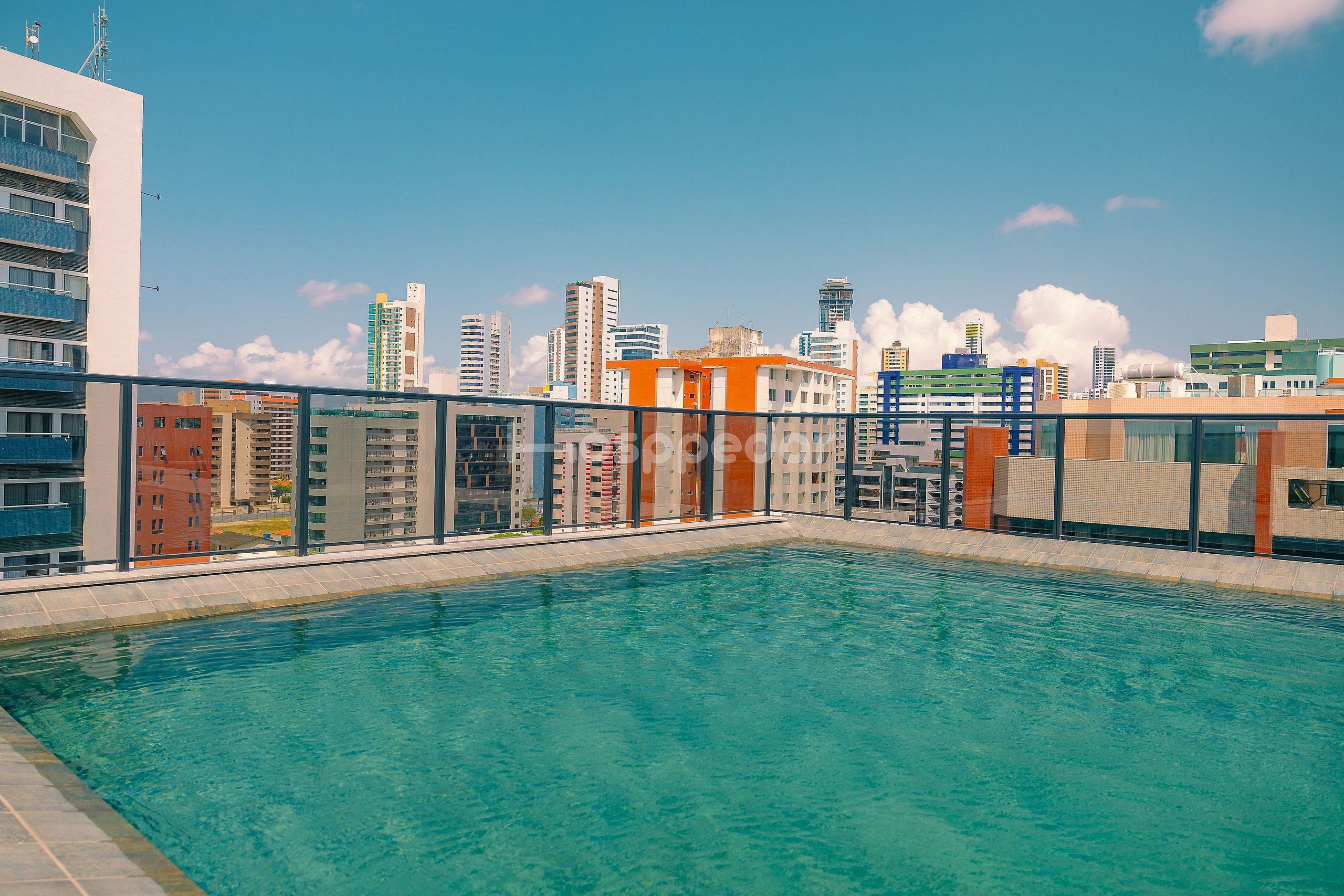 Piscina no terraço com vista para a paisagem urbana, rodeada por edifícios modernos.