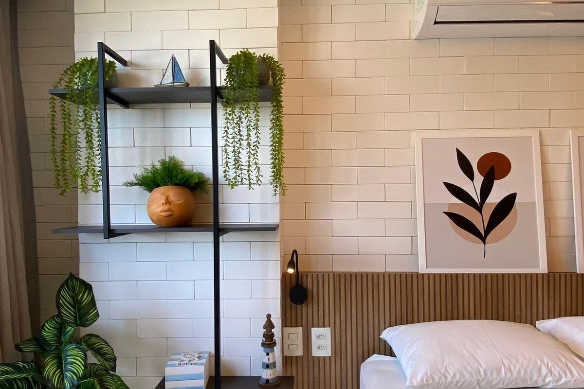 Um quarto moderno com uma cama, uma prateleira fixada na parede com plantas, um objeto decorativo na parede e um aparelho de ar condicionado.