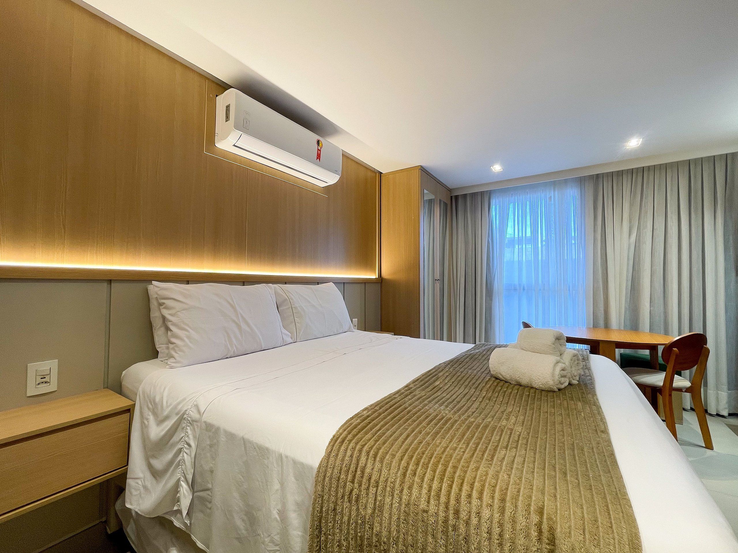 Una camera d'albergo con un letto, un comodino e un condizionatore d'aria.
