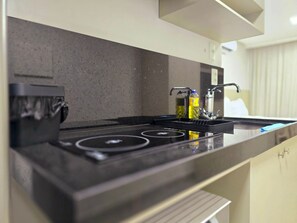 A modern kitchen with a black countertop, stainless steel appliances, and a built-in oven. - Way by Hosppedar (João Pessoa)