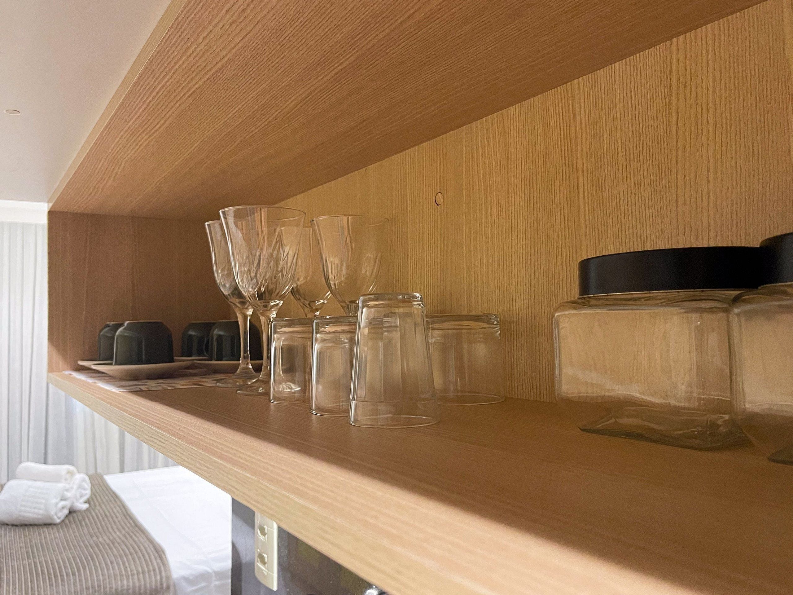 Una estantería de madera con cristalería transparente y un recipiente negro.