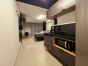 A modern kitchen with a built-in oven, a dining area with a table and chairs, and a bedroom with a bed and curtains. - Way by Hosppedar (João Pessoa)