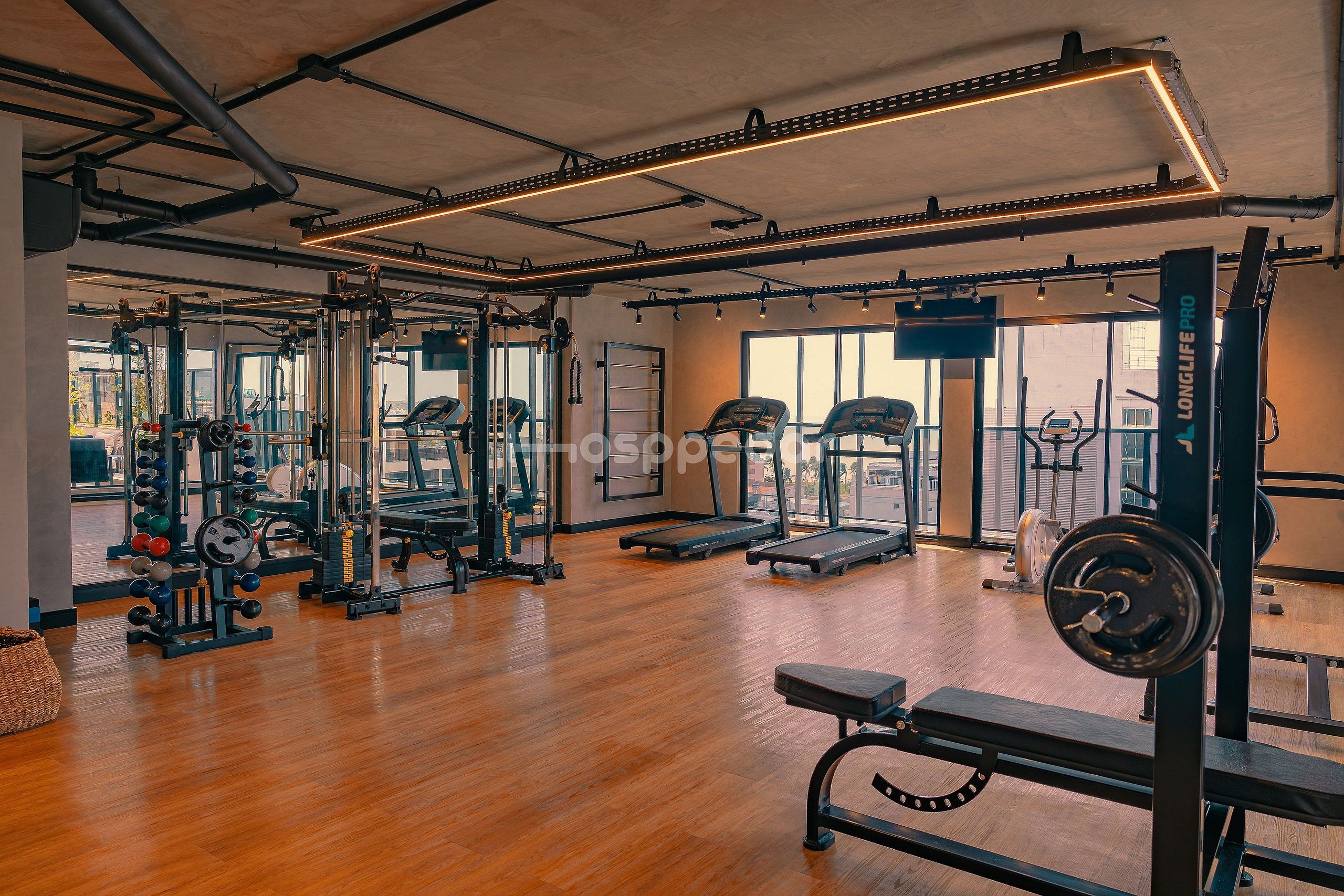 Uma academia com equipamentos de exercício, um banco e esteira.