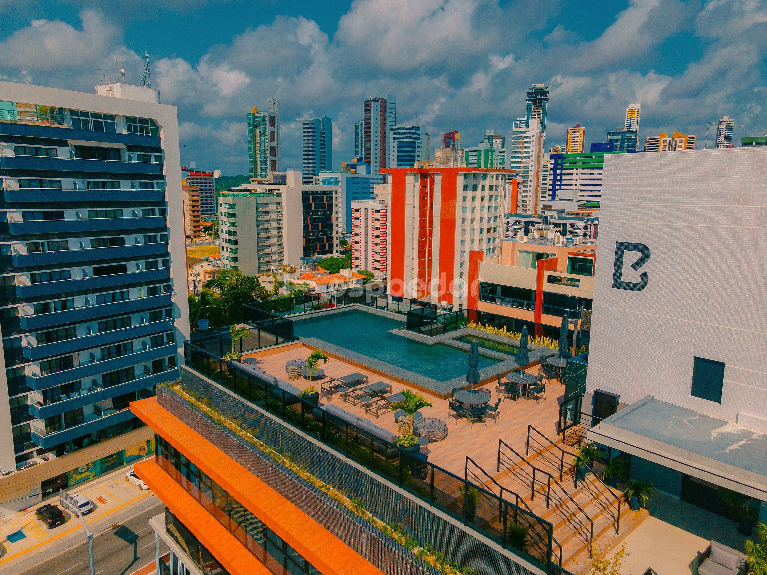 Un immeuble de grande hauteur doté d’une piscine sur le toit, de nombreux balcons et offrant une vue sur le panorama urbain.