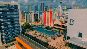 Un edificio alto con piscina sul tetto, numerosi balconi e vista sullo skyline della città.