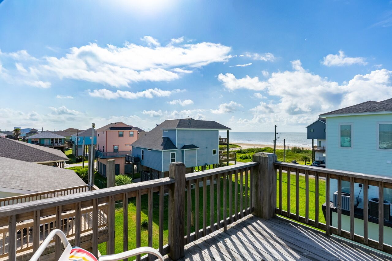 A coastal residential area with houses, a wooden deck, and a view of the beach.