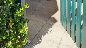 A patio with a table and chairs, a potted plant, a green watering can, and a wooden fence. - Charming one-bedroom apartment for a couple, near the beaches of Capbreton, (Capbreton)