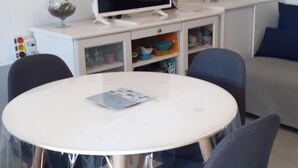 A modern living room with a round table, two chairs, a flat-screen TV, a bookshelf, and a painting on the wall. - Charming one-bedroom apartment for a couple, near the beaches of Capbreton, (Capbreton)