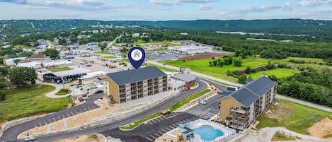 A hotel with multiple buildings, a swimming pool, and a parking area.