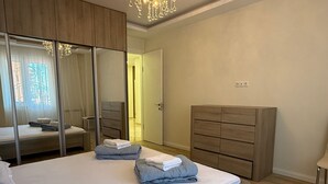 A bedroom with a bed, a wardrobe, a dresser, and a mirror. - Bright Modern 2BR Apt near Central Park & Beach (Batumi)