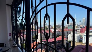 A balcony with a wrought iron railing overlooking a cityscape with red-roofed buildings. - Bright Modern 2BR Apt near Central Park & Beach (Batumi)