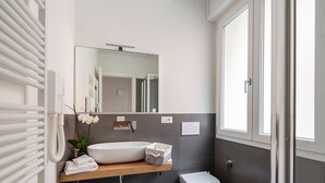 Ein modernes Badezimmer mit Waschbecken, Spiegel, Toilette und Heizkörper.
