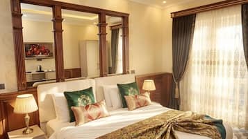 Quarto de hotel com cama grande, duas luminárias de cabeceira, um espelho e vista para o exterior através de cortinas.