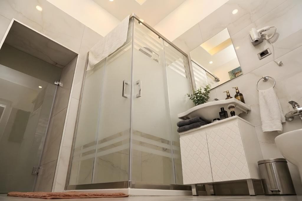 A modern bathroom with a glass-enclosed shower, a white vanity with a mirror, and a large bathtub.