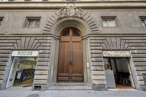 A building with a large wooden door, a wash and dry service, and a bakery named 'La cucina del Gatto e la Volpe'. - Historic Center Apartment - A Walk to Top Attractions (Firenze)