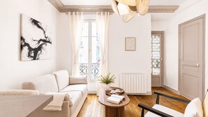 A modern living room with a sofa, coffee table, and a chair. - 1518 Trétaigne (Paris)