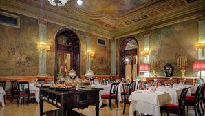 A formal dining room with wooden tables, chairs, and a buffet.