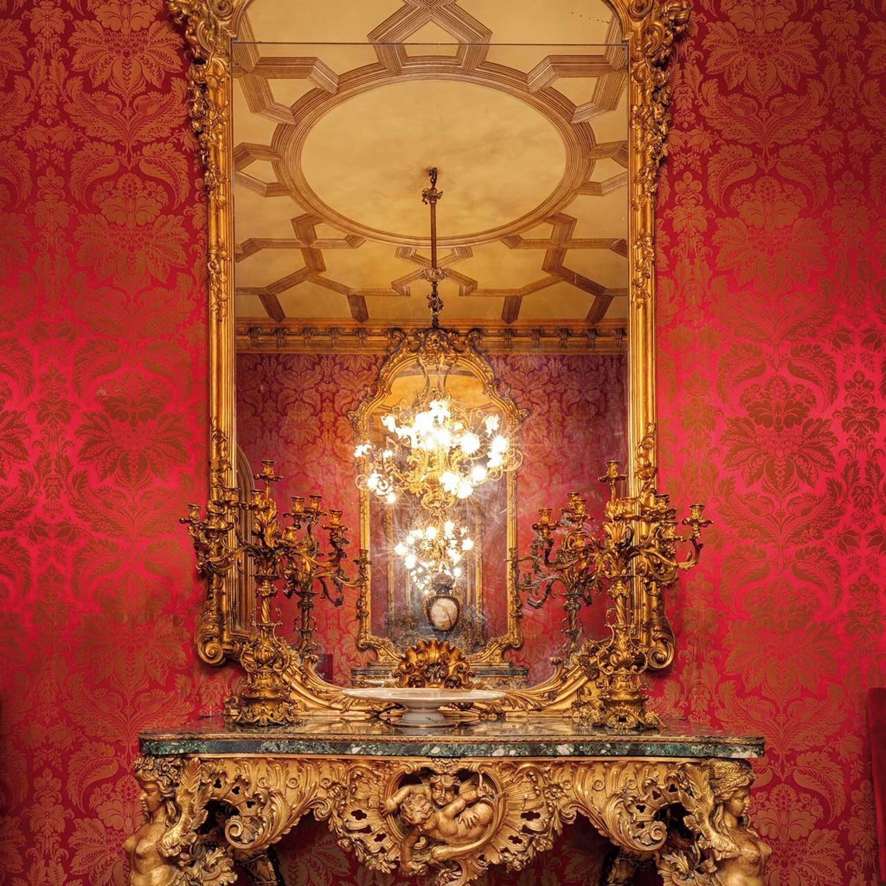 Een sierlijke kamer met een grote spiegel, een kroonluchter en een decoratief tafeltje.