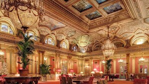 A grand lobby with ornate chandeliers, red carpet flooring, and classical architecture.