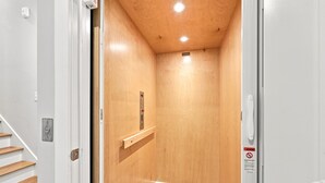 A wooden elevator interior with a control panel, a warning sign, and a wooden floor. - Circle Pearl-Ocean View Townhome (Atlantic Beach)