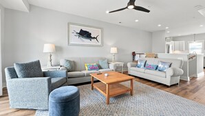 A modern living room with a sofa, armchairs, a coffee table, and a ceiling fan. - Circle Pearl-Ocean View Townhome (Atlantic Beach)