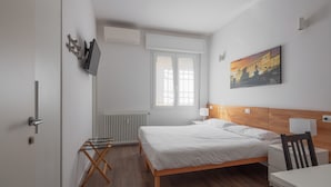 A bedroom with a bed, a desk, a chair, a radiator, a window, and a painting on the wall. - Manzoni Room by Wonderful Italy (Bologna)