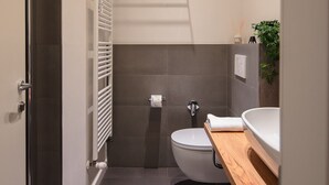 A modern bathroom with a toilet, sink, shower, and towel rack. - Manzoni Room by Wonderful Italy (Bologna)